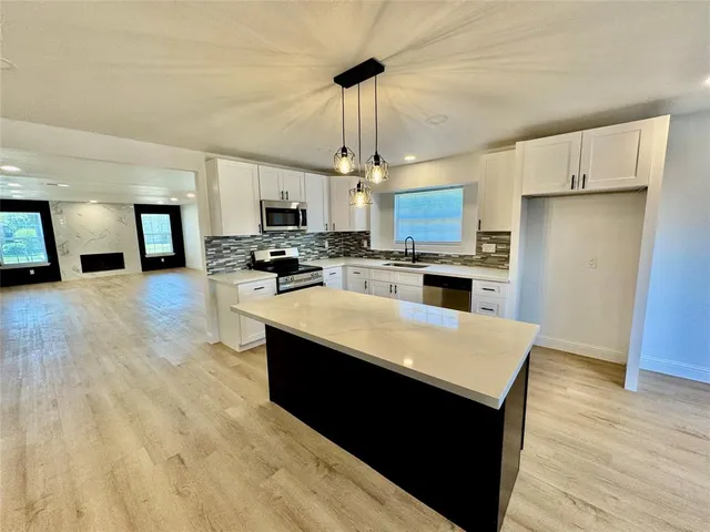 a large kitchen with stainless steel appliances granite countertop a stove and a refrigerator