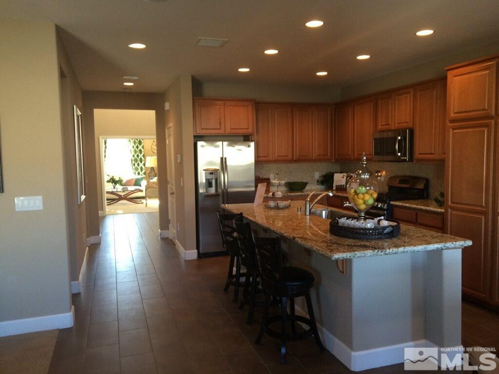1840 Wind Walker Drive Reno, NV 89521 - Photo 3 of 11 a kitchen with kitchen island granite countertop wooden cabinets a dining table and chairs