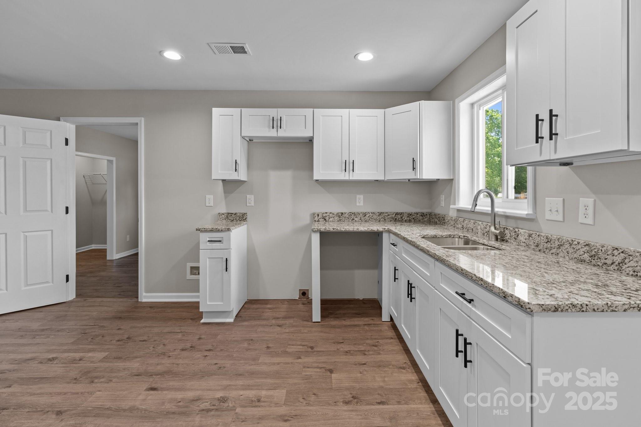 880 Legion Club Road Salisbury, NC 28146 - Photo 7 of 35 a kitchen with granite countertop a sink stove refrigerator and white cabinets with wooden floor