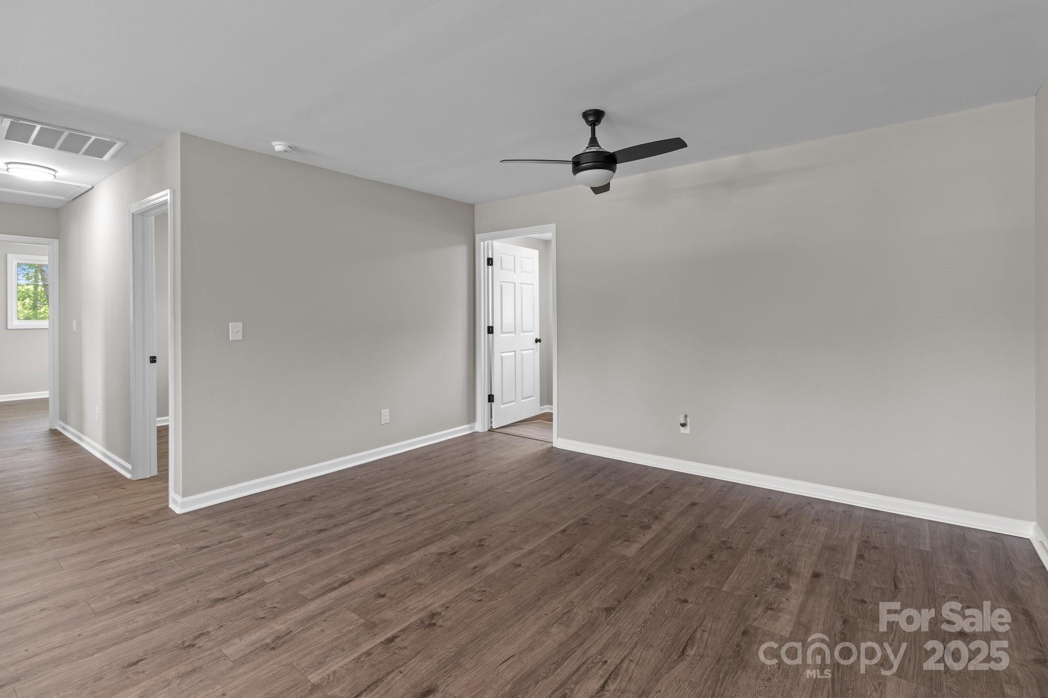 880 Legion Club Road Salisbury, NC 28146 - Photo 9 of 35 an empty room with wooden floor a ceiling fan and windows