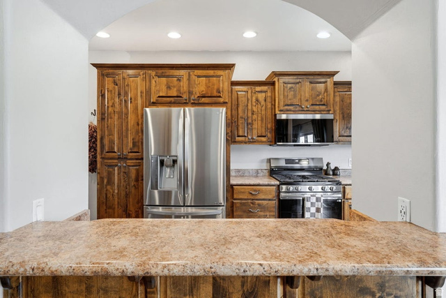 7776 Wagon Road East St. George, UT 84770 - Photo 14 of 76 Kitchen with stainless steel appliances, arched walkways, recessed lighting, wood finish cabinetry, and a peninsula