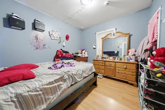 a bedroom with a bed and a mirror on the dresser