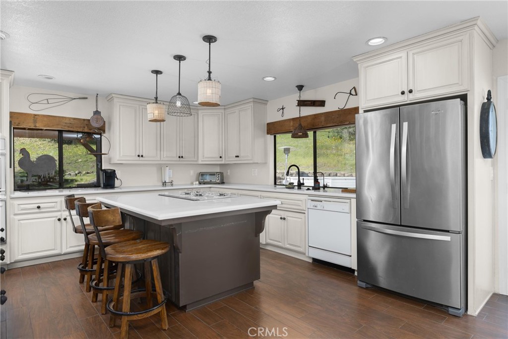 7330 Gage Irving Road Paso Robles, CA 93446 - Photo 10 of 30 a kitchen with kitchen island a sink a stove a refrigerator and white cabinets with wooden floor