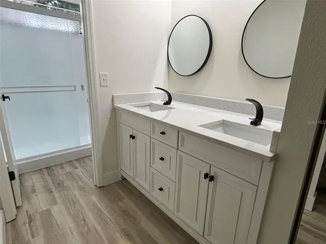 a bathroom with a granite countertop double vanity sink and a mirror