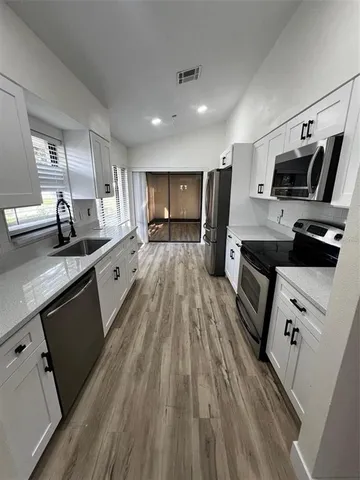 a kitchen with kitchen island granite countertop a sink appliances wooden floor and cabinets