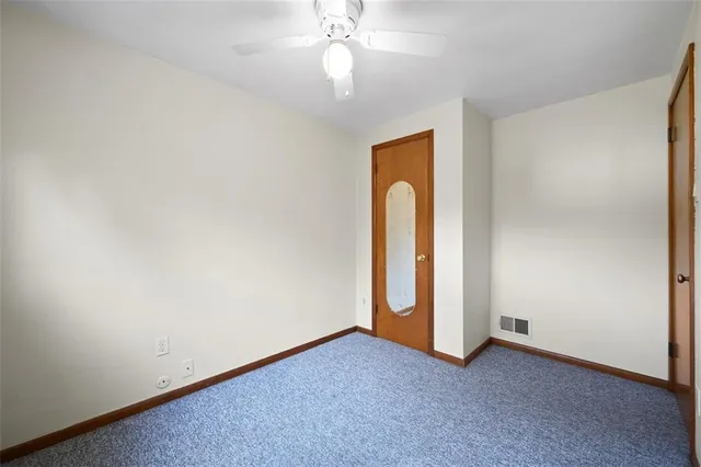 an empty room with a chandelier fan and windows