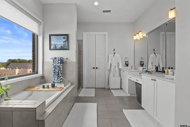 a bathroom with a double vanity sink a large mirror a shower and bathtub
