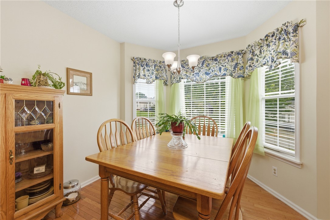 128 Kelly Lane Easley, SC 29642 - Photo 11 of 23 A well-lit dining area offers a welcoming atmosphere for gatherings, featuring warm wood flooring and a bay window.