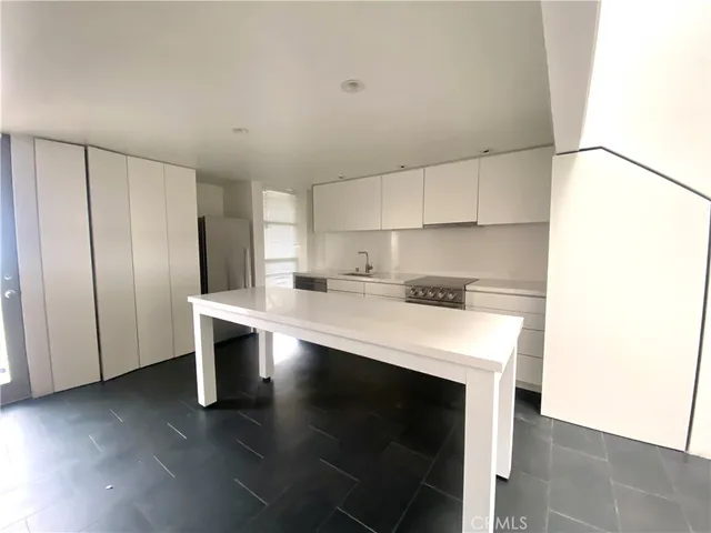 a kitchen with kitchen island a white counter top and refrigerator