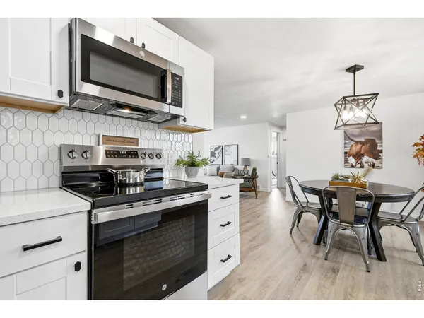 a kitchen with stainless steel appliances granite countertop a stove top oven a sink dishwasher a dining table and chairs with wooden floor