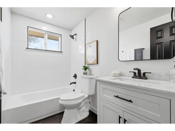 a bathroom with a bathtub sink vanity mirror and toilet
