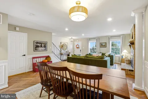 a view of a dining room and livingroom with furniture wooden floor a rug a flat screen tv a painting and a chandelier