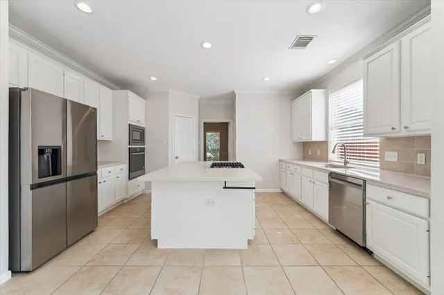 a large kitchen with stainless steel appliances kitchen island granite countertop a stove a sink and a refrigerator