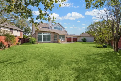a view of a house next to a big yard and large trees