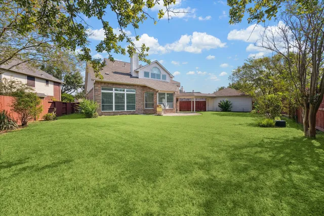 a view of a house next to a big yard and large trees