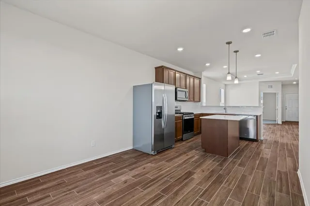 a kitchen with stainless steel appliances kitchen island wooden floors granite counter tops and a window