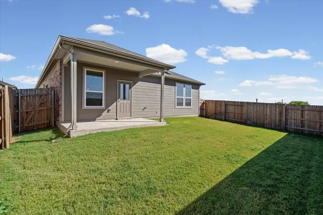 a view of a house with backyard and wooden fence