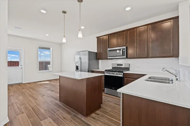 a kitchen with stainless steel appliances granite countertop a sink a stove and a refrigerator