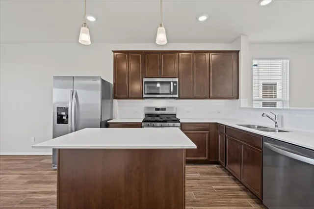 a kitchen with stainless steel appliances a sink dishwasher a refrigerator and a stove with wooden floor