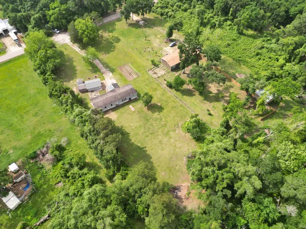 an aerial view of residential house with outdoor space and trees all around