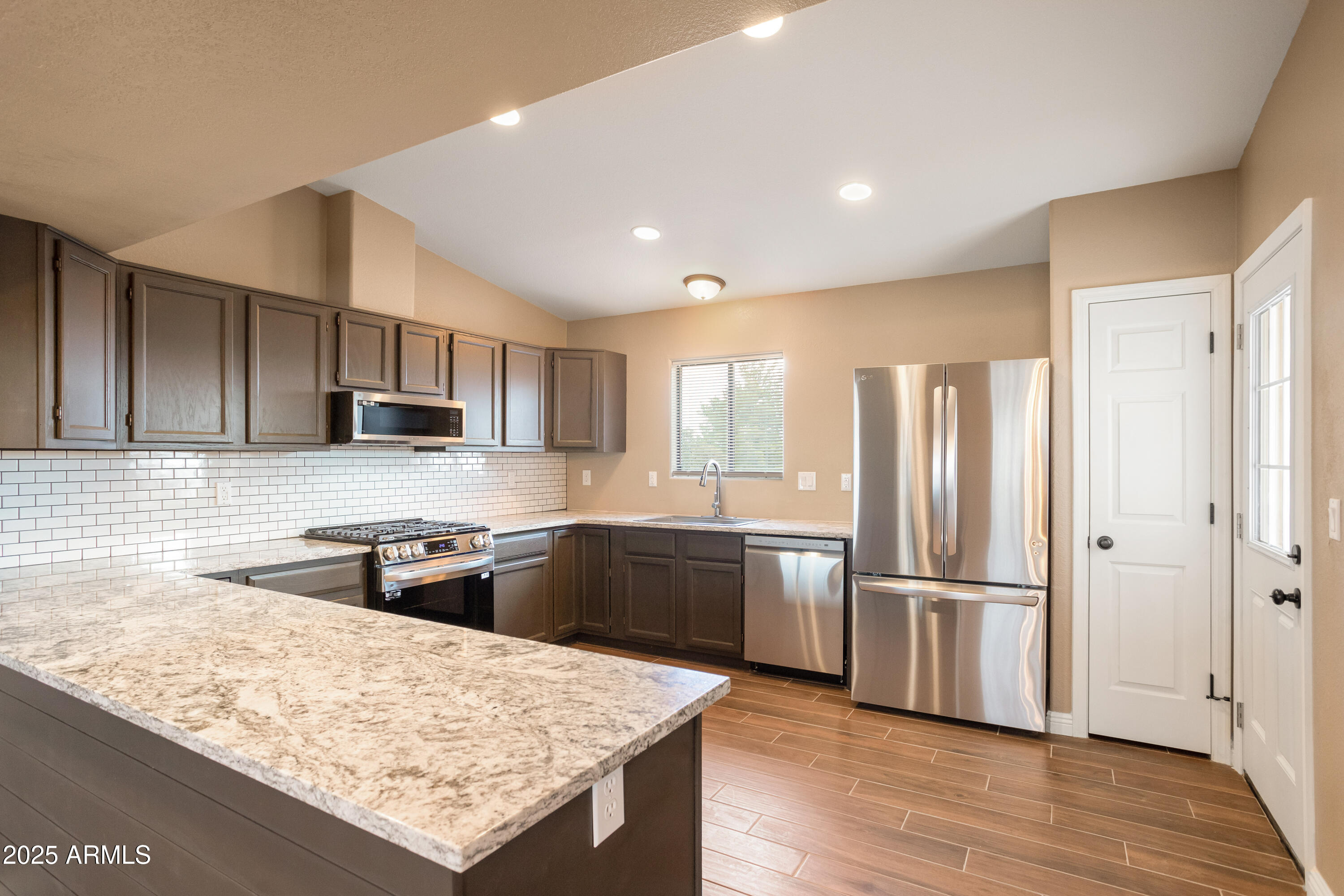 5837 South Wild Rose Road Hereford, AZ 85615 - Photo 7 of 46 a kitchen with stainless steel appliances granite countertop a refrigerator a sink dishwasher a stove and white countertops with wooden floor