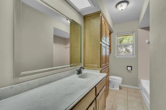 a bathroom with a granite countertop sink a toilet and a mirror
