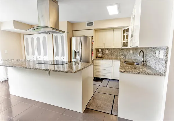 a kitchen with granite countertop a sink a stove top oven and cabinetry