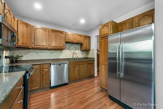 a kitchen with stainless steel appliances granite countertop a refrigerator a sink and a stove