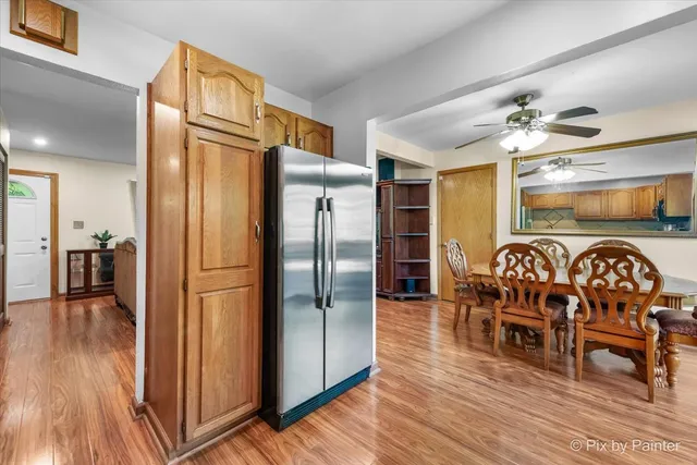 a kitchen with stainless steel appliances granite countertop a dining table chairs refrigerator and sink