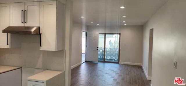 a view of a hallway with wooden floor and a bathroom