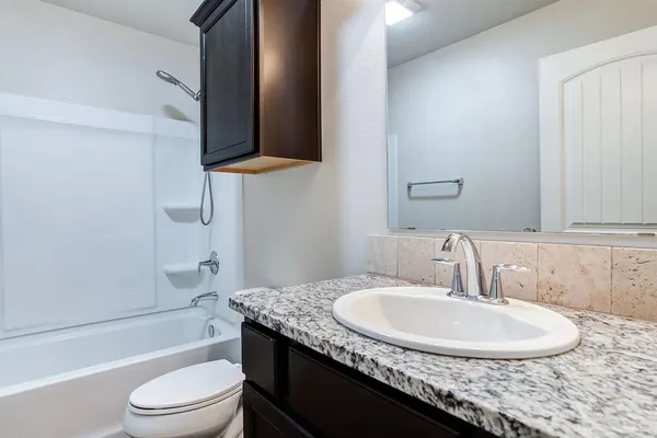 a bathroom with a granite countertop sink a light fixture and a mirror