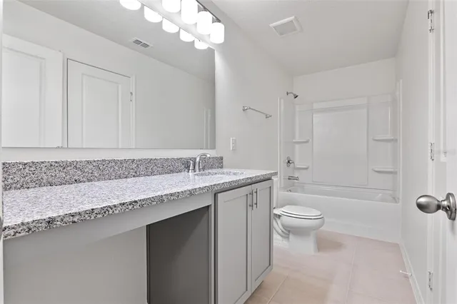 a bathroom with a granite countertop sink a toilet and bathtub