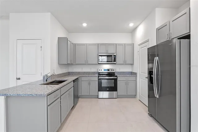 a kitchen with kitchen island granite countertop stainless steel appliances and refrigerator