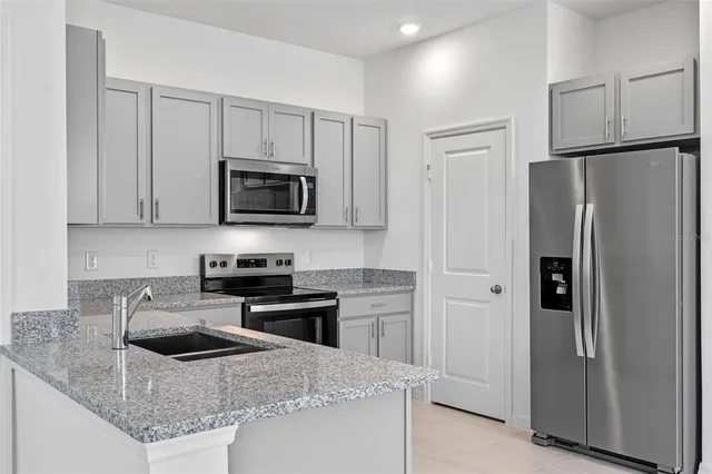a kitchen with granite countertop a refrigerator and a sink