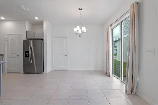 a view of a hallway with chandelier and a refrigerator