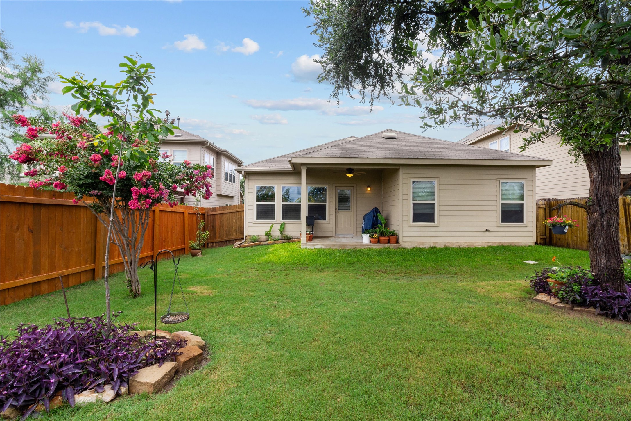 10413 Crescendo Lane Austin, TX 78747 - Photo 25 of 32 A neatly maintained backyard oasis boasts a covered patio, vibrant landscaping, and durable wood fencing.