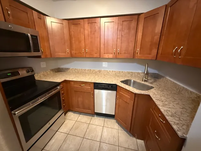 a kitchen with granite countertop a sink dishwasher stove and cabinets with wooden floor
