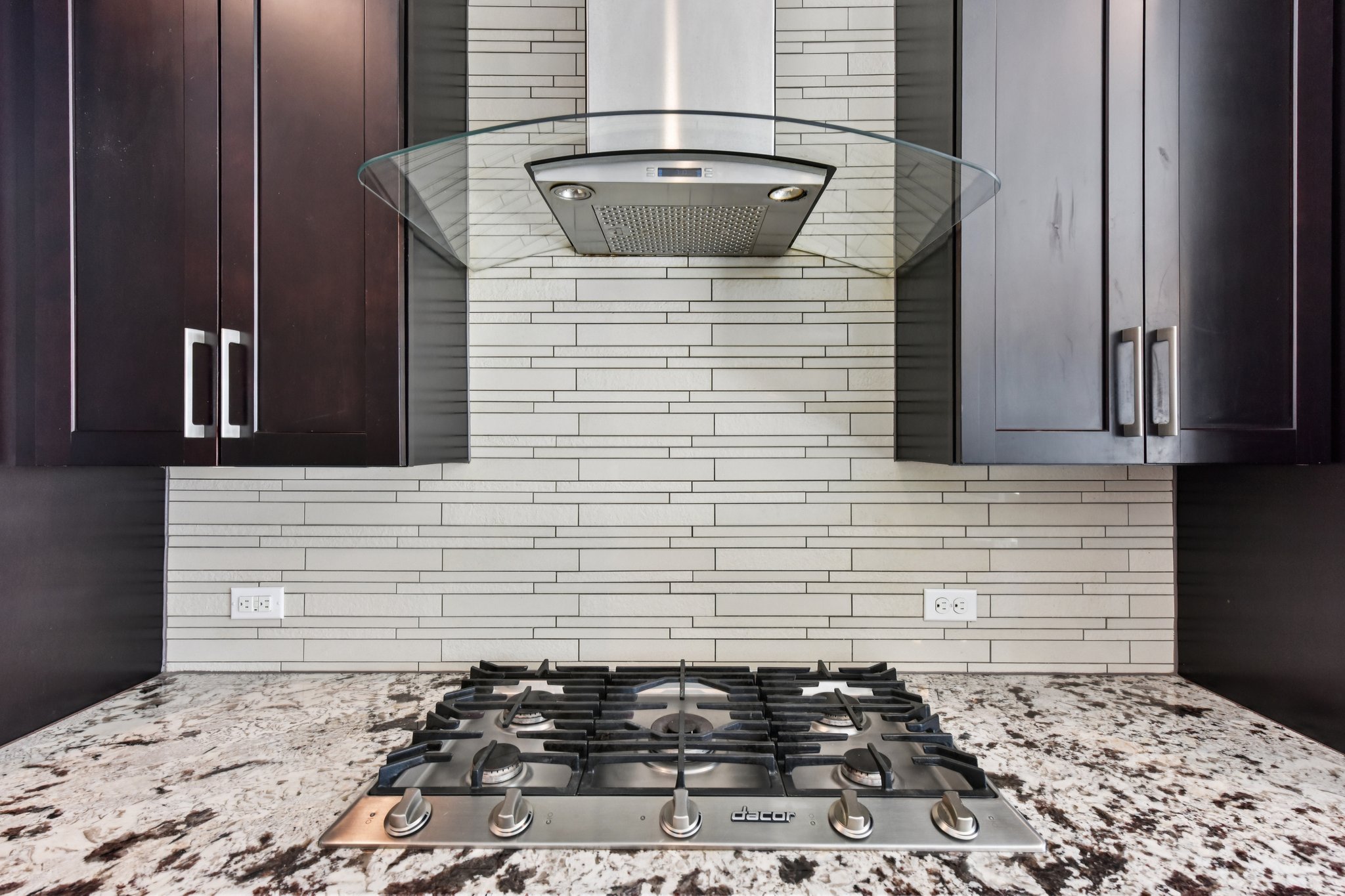 8110 Ranch Road 2222, Unit 98 Austin, TX 78730 - Photo 11 of 37 Kitchen view of exhaust hood, light stone counters, stainless steel gas stovetop, and backsplash