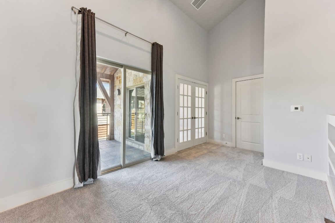 8110 Ranch Road 2222, Unit 98 Austin, TX 78730 - Photo 17 of 37 Spare room featuring high vaulted ceiling, light carpet, and french doors