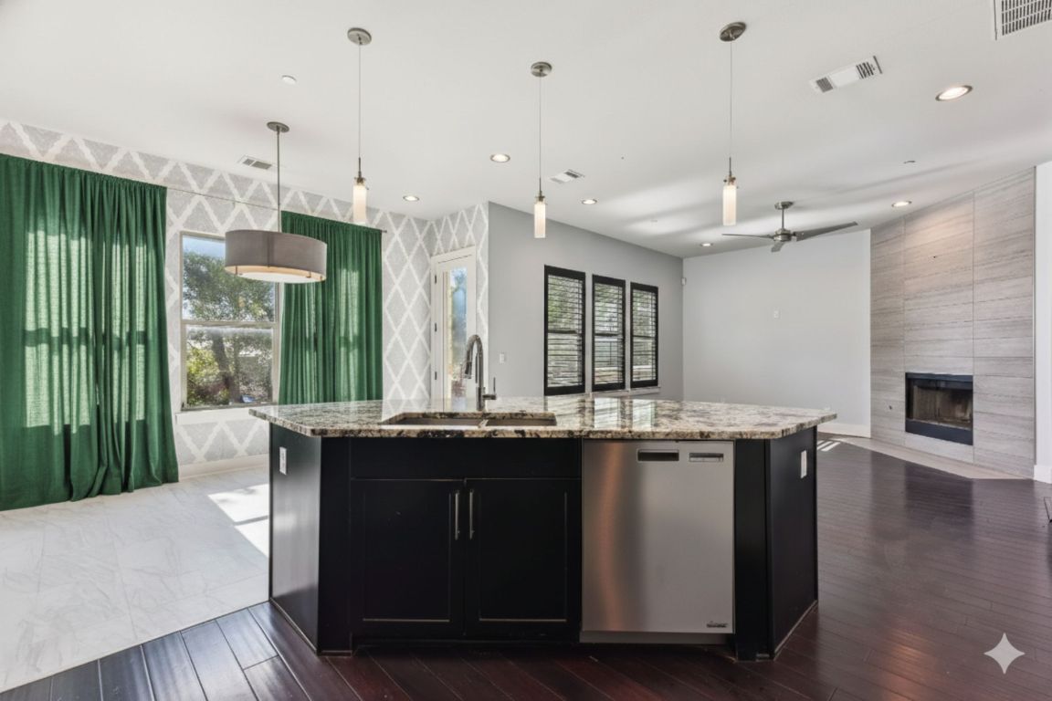 8110 Ranch Road 2222, Unit 98 Austin, TX 78730 - Photo 37 of 37 Kitchen featuring dark cabinetry, hanging light fixtures, stainless steel dishwasher, open floor plan, and an island with sink