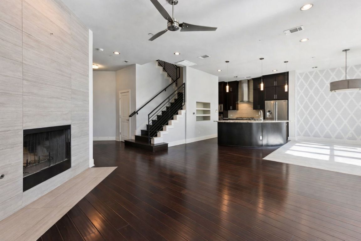 8110 Ranch Road 2222, Unit 98 Austin, TX 78730 - Photo 6 of 37 Unfurnished living room with stairway, a tiled fireplace, dark wood finished floors, a ceiling fan, and recessed lighting