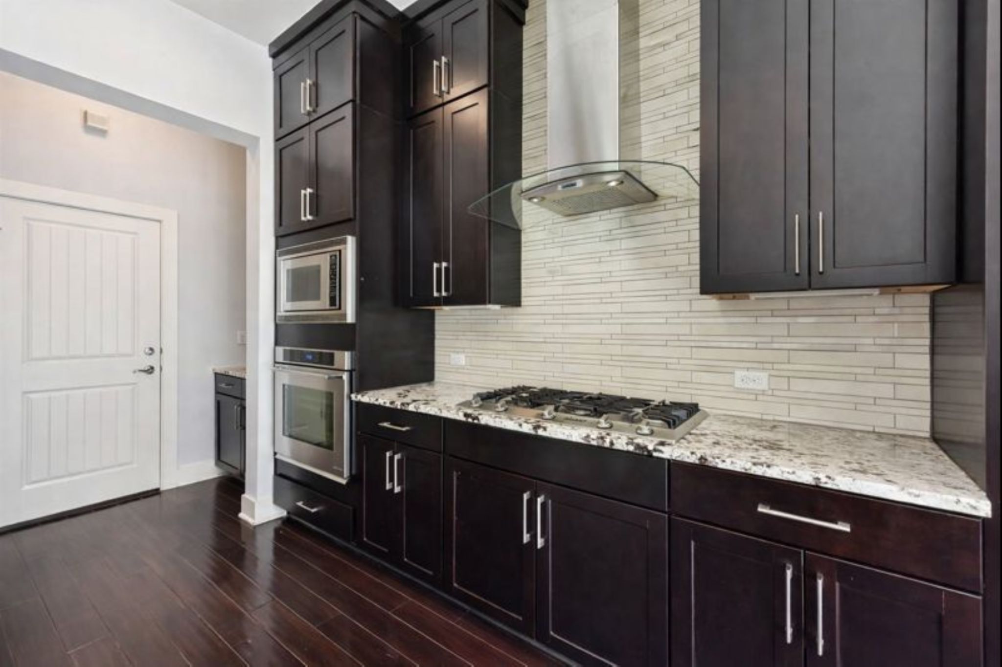 8110 Ranch Road 2222, Unit 98 Austin, TX 78730 - Photo 8 of 37 Kitchen featuring wall chimney exhaust hood, stainless steel appliances, light stone countertops, and dark wood-style floors