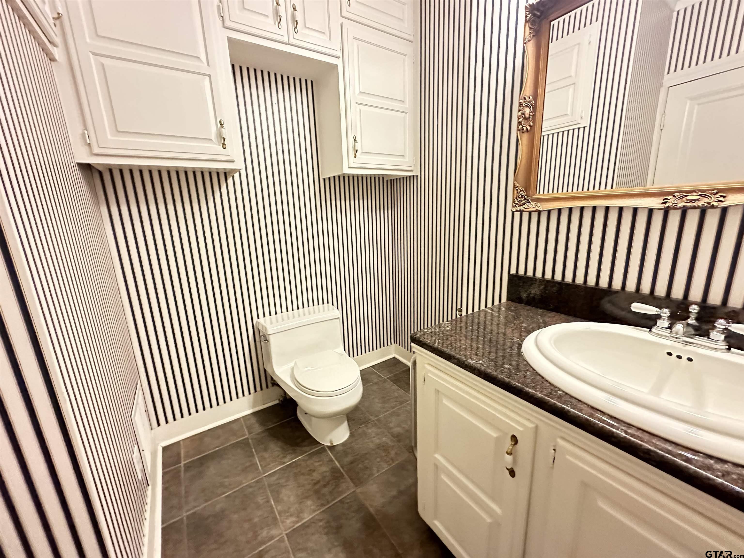 2337 East Rusk Street Jacksonville, TX 75766 - Photo 18 of 47 a bathroom with a sink a toilet and a window