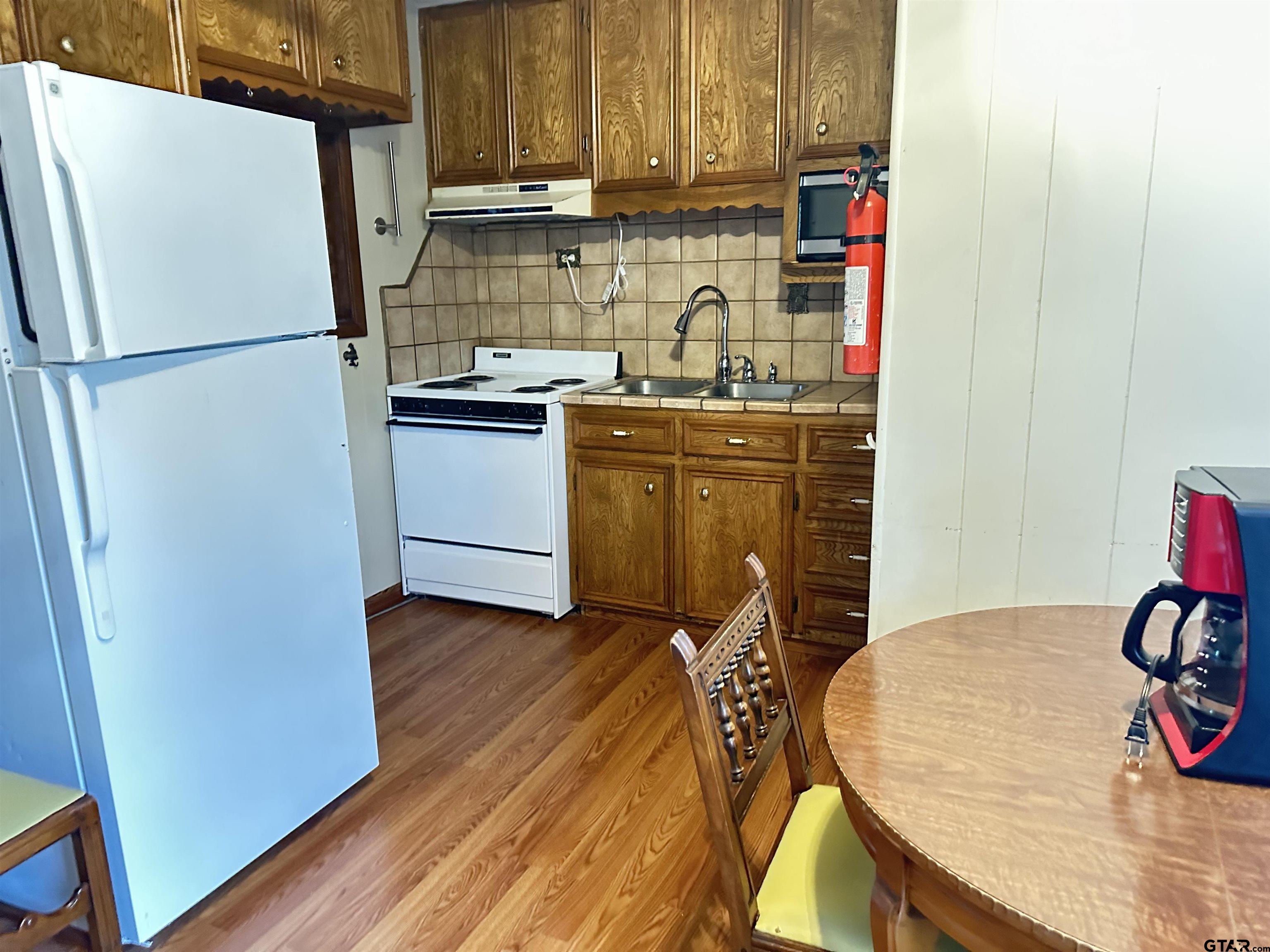 2337 East Rusk Street Jacksonville, TX 75766 - Photo 35 of 47 a kitchen with wooden floors and refrigerator