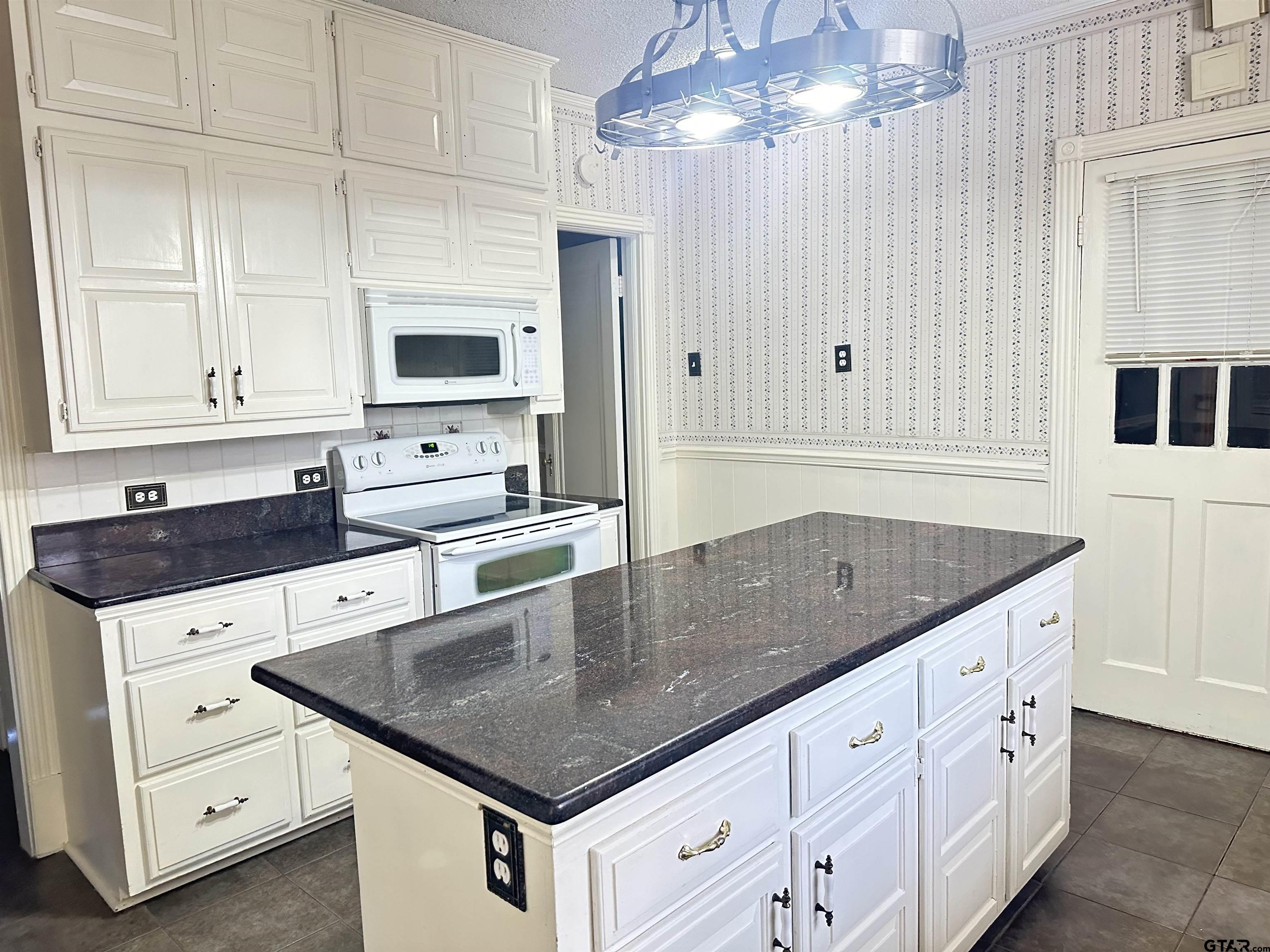 2337 East Rusk Street Jacksonville, TX 75766 - Photo 8 of 47 a kitchen with granite countertop a sink a stove and a microwave oven