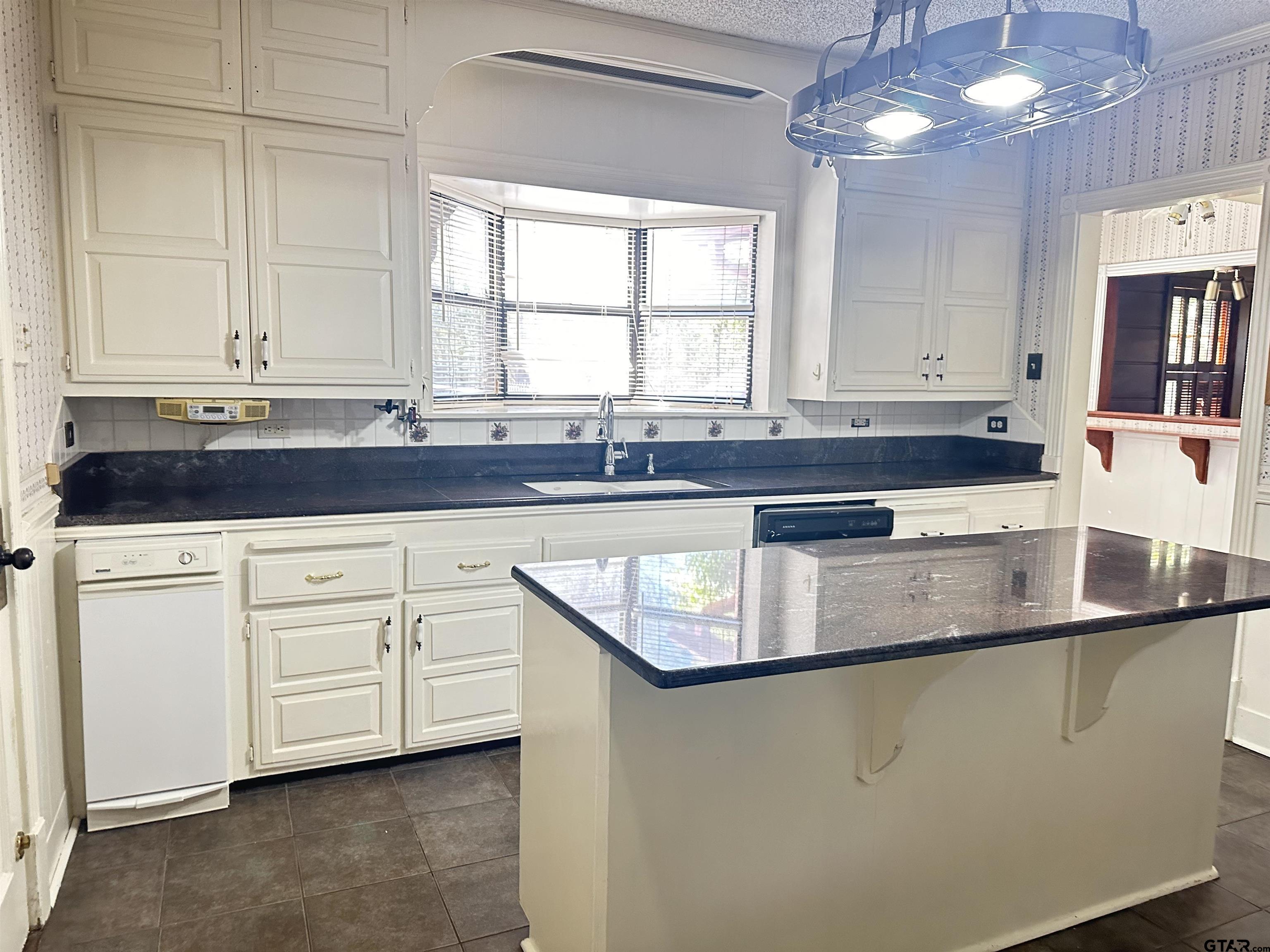 2337 East Rusk Street Jacksonville, TX 75766 - Photo 10 of 47 a kitchen with granite countertop a sink a window and white cabinets