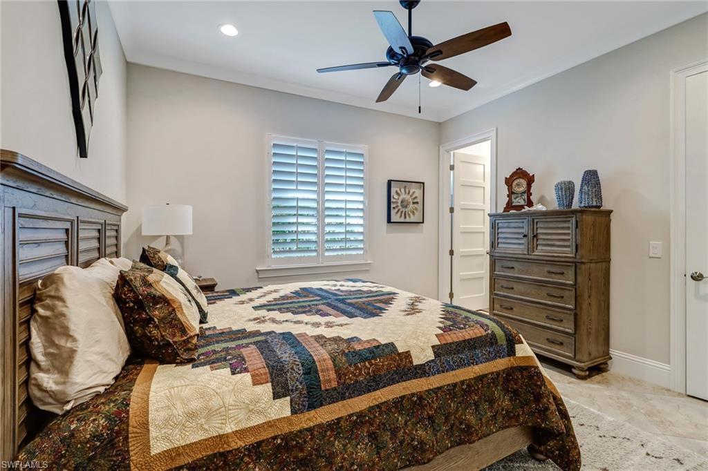 6487 Warwick Avenue Naples, FL 34113 - Photo 17 of 32 a bedroom with a bed and a chandelier