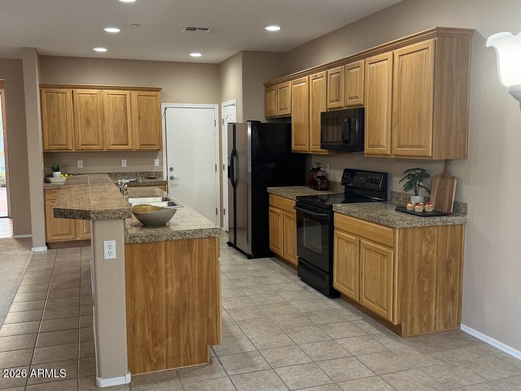 3330 West Ravina Lane Anthem, AZ 85086 - Photo 6 of 29 a kitchen with stainless steel appliances granite countertop wooden cabinets a stove a sink and a microwave