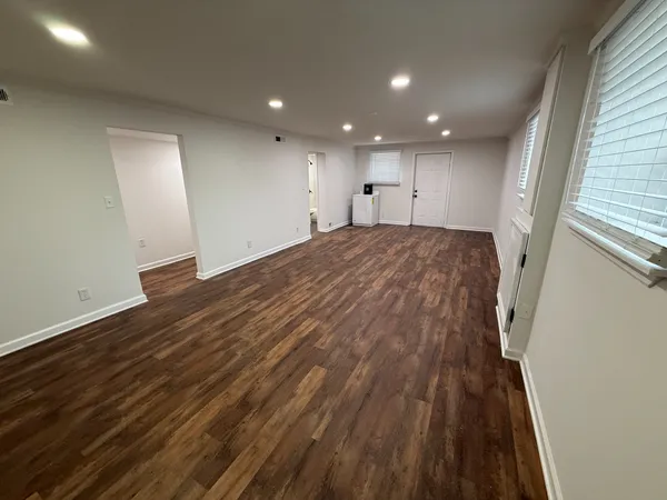 an empty room with wooden floor and windows