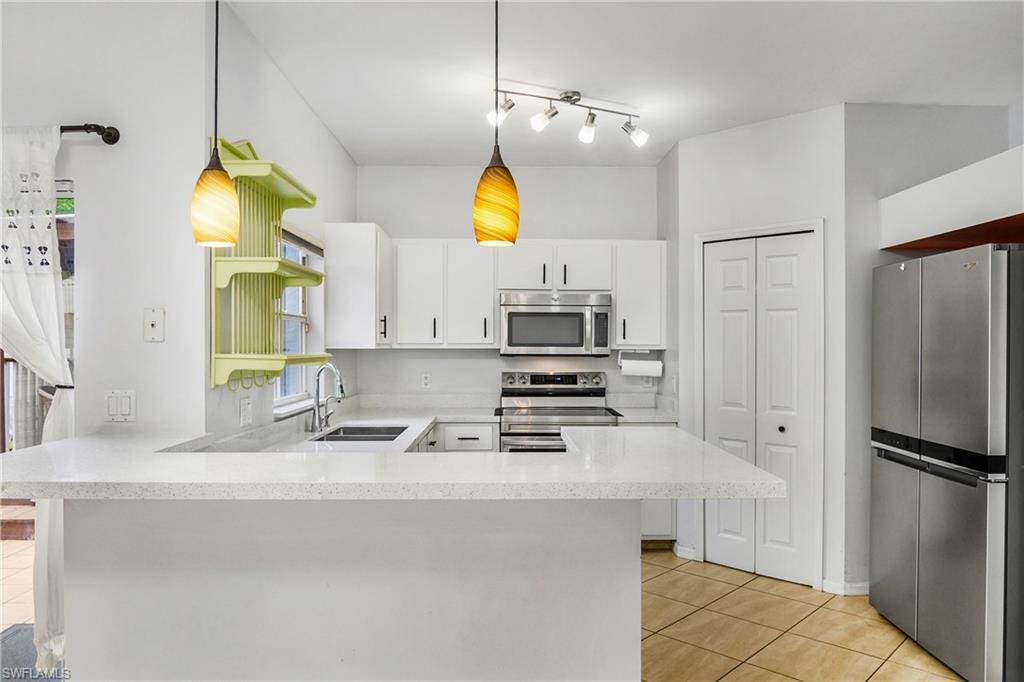 18230 Heather Road Fort Myers, FL 33967 - Photo 10 of 28 Kitchen with stainless steel appliances, a peninsula, light tile patterned flooring, and white cabinets